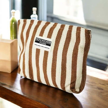 Pochette Novacare à rayures, idéale pour transporter vos essentiels de soins avec élégance.